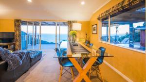 a dining room with a table and chairs and the ocean at Romantic Piha in Piha