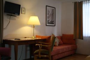 una camera d'albergo con scrivania, divano e lampada di Dorfgasthof "Zur Rose" a Obereisenheim