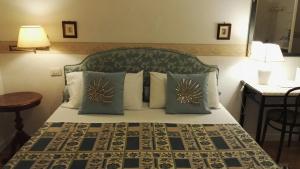 Schlafzimmer mit einem Bett mit einem grünen Kopfteil und Kissen in der Unterkunft B&B Maison A in Cagliari