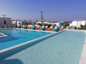 une grande piscine avec des chaises et des parasols bleus dans l'établissement Pelagos Studios, à Platis Gialos