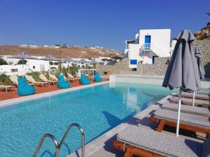 a swimming pool with chairs and an umbrella at Pelagos Studios in Platis Yialos Mykonos