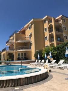 a hotel with a swimming pool and chairs and a building at Villa Laguna in Sutomore