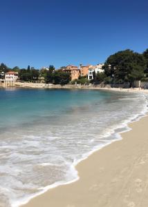 una spiaggia con l'oceano e edifici sullo sfondo di Les Hameaux de Provence - Piscine et place de Parking privée - Accès plage et sentier du littoral a Bandol