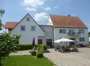 a white house with a table and an umbrella at Ferienbauernhof Schuler in Gunzenhausen