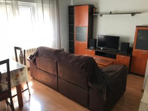 - un salon avec un canapé brun et une télévision dans l'établissement Apartamento low cost, à Gijón