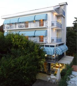 um edifício com guarda-chuvas azuis e brancos à sua frente em Hotel Vera em Riccione