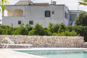 ein Haus mit einer Steinmauer neben einem Pool in der Unterkunft Masseria Guadiano Vecchio in Santa Lucia