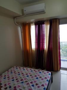 a bedroom with a bed with colorful curtains and a window at Milagrosa(SMDC wind residences) in Tagaytay