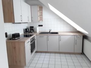 uma pequena cozinha com armários brancos e uma escadaria em Ferienwohnung Osterheide em Schneverdingen