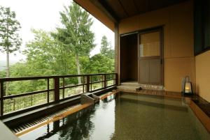 a room with a pool of water and a balcony at Kofukan in Myoko