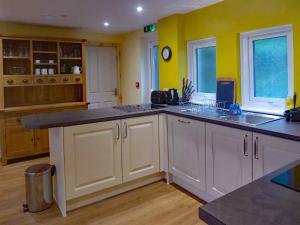 a kitchen with white cabinets and yellow walls at Bryn Melyn Apartments in Barmouth