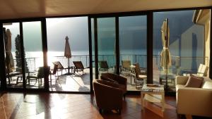 ein Wohnzimmer mit einem Balkon mit Stühlen und Tischen in der Unterkunft Hotel Mercedes in Limone sul Garda