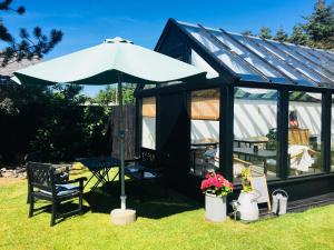 a black and white shed with a table and an umbrella at Villa Vendel B&B in Løkken