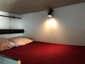 una camera con letto rosso e luce sul muro di Modern cozy studio with backyard ad Anversa