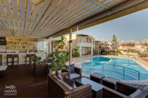 a resort with a swimming pool and tables and chairs at Corinna Mare in Kalamaki