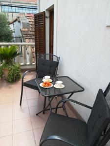 una mesa y sillas en un balcón con un bol de fruta. en Apartment Diocletians Split Center en Split