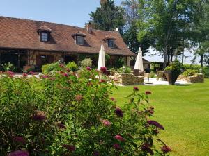 una casa con un patio con flores y sombrillas en Le Venay, en Frontenaud