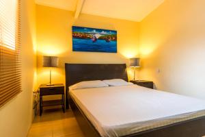 a bedroom with a bed with two night stands and two lamps at Advantage Apartments Curacao in Willemstad