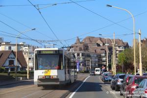 a bus is driving down a city street with cars at De Panne Plaza in De Panne
