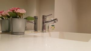 La salle de bains est pourvue d'un lavabo avec un robinet et de 2 vases fleuris. dans l'établissement 2BEDS Melbourne Central|Crown Casino|Colin|S Cross, à Melbourne