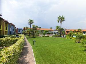 a park with palm trees and houses in the background at Porto Antico Village in Aprilia Marittima