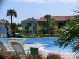 a resort swimming pool with chairs and palm trees at Porto Antico Village in Aprilia Marittima