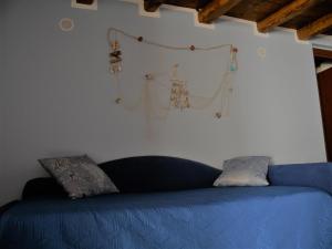 Un sofá azul contra una pared blanca con algunos artículos. en A Vanedda en Termini Imerese