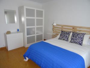 a bedroom with a large bed with blue and white pillows at Apartamento en O Grove in O Grove