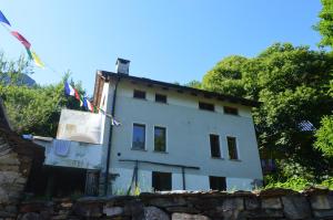 a white house with flags on top of it at Secret Mountain Retreat Valle Cannobina (for nature Lovers only) in Orasso