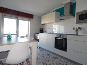 a kitchen with white cabinets and a table with chairs at Apartamento en O Grove in O Grove