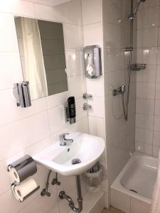 a white bathroom with a sink and a shower at Hotel Moji Köln in Cologne