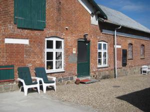 Deux chaises assises à l'extérieur d'un bâtiment en briques dans l'établissement Farmer Annekset Ravning, à Bredsten