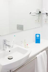 Baño blanco con lavabo y espejo en Live & Dream, en Barcelona