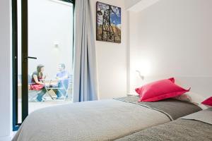 1 dormitorio con 1 cama con almohadas rojas y balcón en Live & Dream, en Barcelona