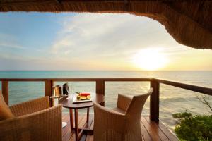 een tafel en stoelen op een balkon met uitzicht op de oceaan bij Melia Zanzibar in Kiwengwa