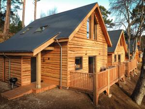 a large wooden cabin with a black roof at Cairngorm Lodge in Aviemore