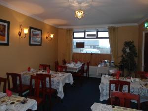 a restaurant with white tables and chairs and a window at Causeway tavern bed & breakfast in Bushmills