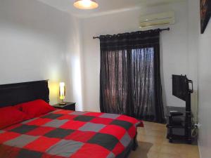 - une chambre avec un lit rouge et noir et une fenêtre dans l'établissement Chez Younès Appartement Marina Saidia Ap2, à Saïdia