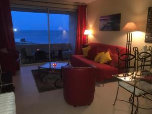 a living room with a red couch and a large window at Res Port St.Ange in Le Barcarès