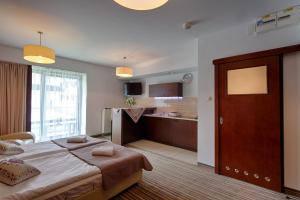 a bedroom with a large bed and a kitchen at Apartament Szklane Domy in Zakopane