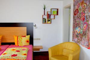 a bedroom with a bed and a yellow chair at Donau Pension in Tuttlingen