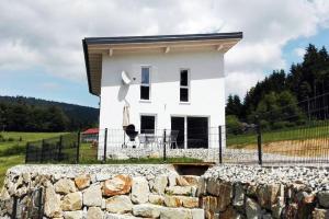 a white house with a stone wall in front of it at Ferienhaus Grobauer II in Schwarzenberg am Bohmerwald