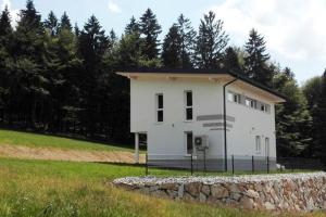 ein weißes Haus mit einer Steinmauer auf einem Feld in der Unterkunft Ferienhaus Grobauer II in Schwarzenberg am Bohmerwald