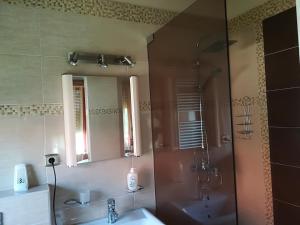 a bathroom with a shower and two sinks and a mirror at Betty Apartman in Balatonfůzfő