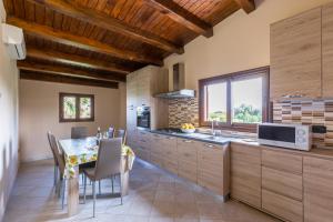 a kitchen with wooden cabinets and a table with chairs at Villa Stefy in Avola