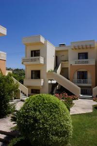 a large white building with balconies and a bush at Olga Suites in Maleme