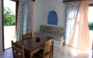 ein Esszimmer mit einem Tisch, Stühlen und Fenstern in der Unterkunft Olga Suites in Maleme