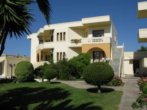 a large white building with trees and bushes at Olga Suites in Maleme
