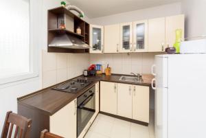 a kitchen with white cabinets and a white refrigerator at Breki Apartman in Podstrana