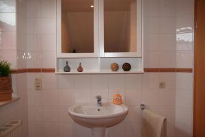 a white bathroom with a sink and a cabinet at Wunderschöne Landhauswohnung in Rinteln in Rinteln +1 photo